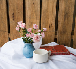 Outdoor patio patio setting sweetly with blue vase filled with pink rose. A cup of coffee would be nice too