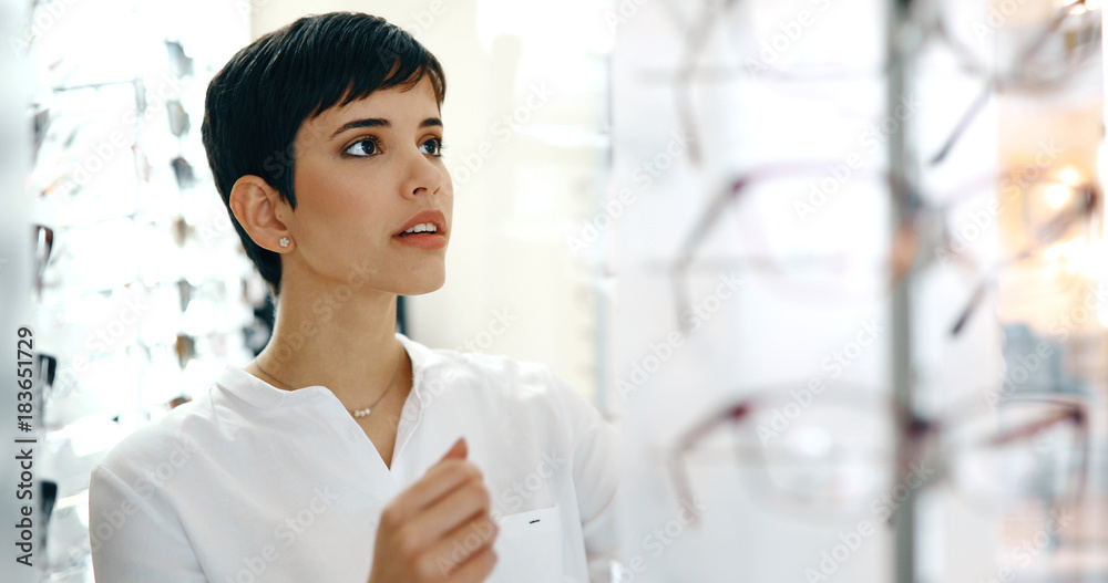 Wall mural health care, eyesight and vision concept - happy woman choosing glasses at optics store