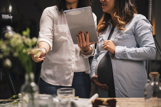 Pregnant woman with a colleague working on a food photoshoot in a studio