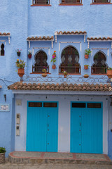 Fototapeta na wymiar Traditional moroccan courtyard in Chefchaouen blue city medina in Morocco, architectural details in Blue town Chaouen. Typical blue walls and colorful flower pots.