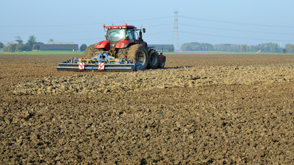 Fototapeta premium Farmer is harrowing in clay soil