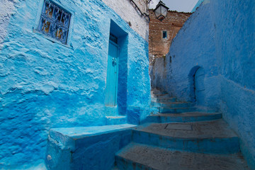 Traditional moroccan courtyard in Chefchaouen blue city medina in Morocco, architectural details in Blue town Chaouen. Typical blue walls and colorful flower pots.