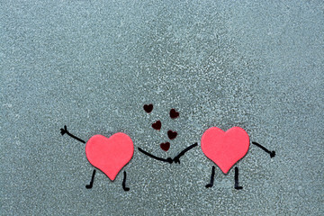 Two red hearts holding hands on a gray background. Hearts with painted hands and feet. Loving hearts