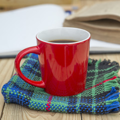 Red cup of coffee and books opened diary on wooden table.