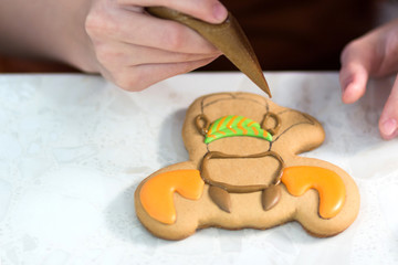 The child decorates cookies in the form of a deer or elk using a confectionery bag with glaze.
