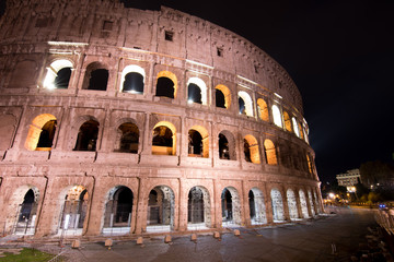 A police car patrols past the Colosseum at night