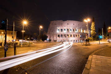 Fototapeta na wymiar City traffic passes by the Colosseum at night