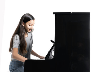 teenage brunette girl and black upright piano against white background in studio