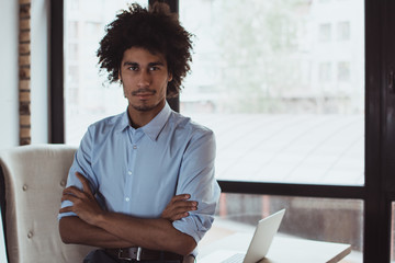 Elegance and confidence. Handsome young businessman looking at camera while sitting at his office desk