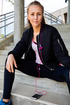 Woman In Sportswear Listening Music On Mobile Phone At Stairway