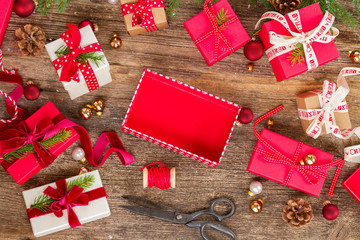 Christmas gift giving - pile of wrapped in red and white paper christmas gift boxes with open and empty one on wooden background