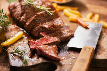 Grilled medium rare beef steack served on wooden rustic board