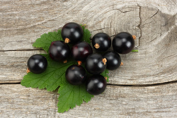 black currant with green leaf on old wooden background. top view