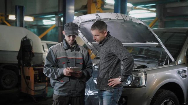 Two men are talking in auto repair shop
