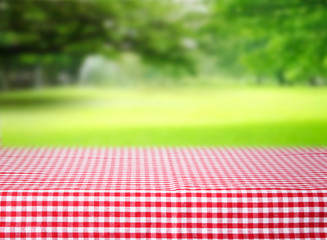 Checkered red tablecloth emty space table green background.