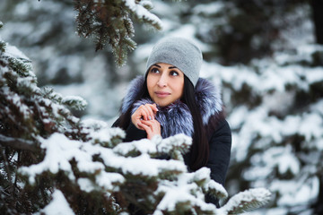 Winter portrait of young beautiful brunette woman wearing warm clothes. Snowing winter beauty fashion concept