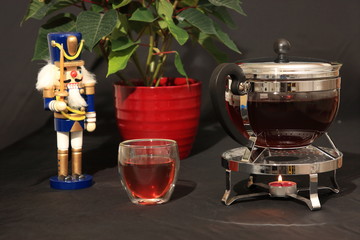 nussknacher und teekanne vor poinsettia flower mit schwarzem hintergrund