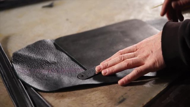 close up shot of the sewing process, the man draws even lines on a piece of leather, the master is engaged in making hend things in his home workshop