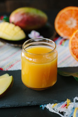 Fresh mango and orange detox drink over black slate.