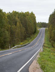 Fototapeta premium Straight asphalt road in Finland. Yellow and white marks.