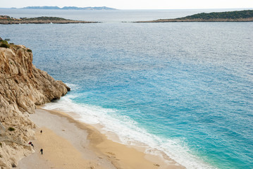 View down onto beach and sea, with people sunbathing. Kaputas, Turkey.
