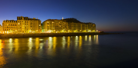 Obraz premium The lights of the city of San Sebastian are reflected in the sea water at night