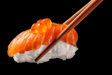 Fotobehang Zalm sushi nigiri in eetstokjes geïsoleerd op zwarte achtergrond. Close-up. © Vadim
