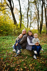 Fototapeta premium Happy caucasian family of mom dad and little girl with boy at majestic autumn fall forest.