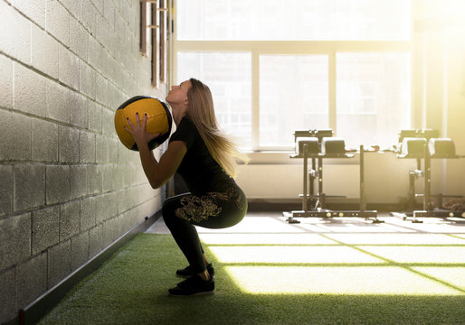 Woman doing exercise with heavy medicine ball in gym