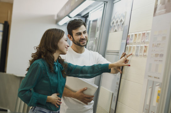 Couple Choosing Tiles In Ceramic And Furniture Shop For New Home