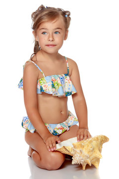 Little girl in a swimsuit with a seashell