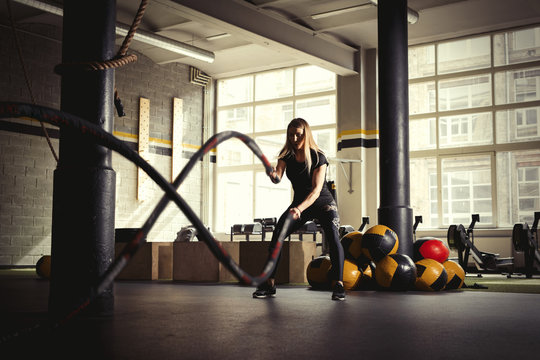 Woman training with battle ropes in gym