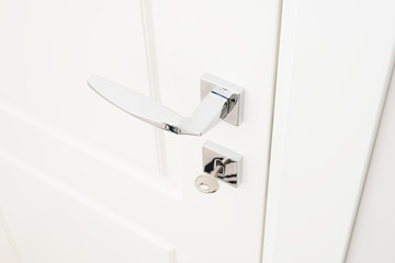 Modern door handle and escutcheon for lock with key. Chrome interior details in close-up
