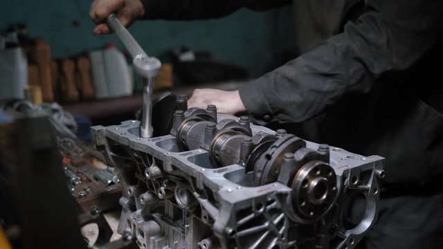 Mechanic repairs engine block in a garage.