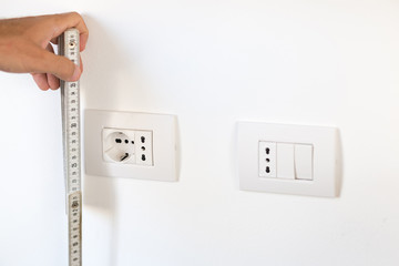 Electrician taking measures of some sockets. Home maintenance and design concepts