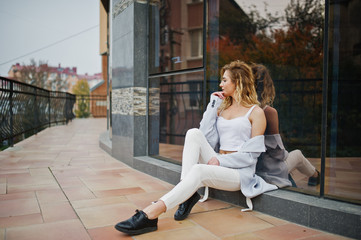 Stylish curly blonde model girl wear on white posing against large window.