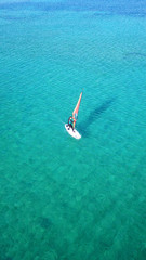 Aerial drone bird's eye view of man surfing in paradise tropical turquoise clear waters