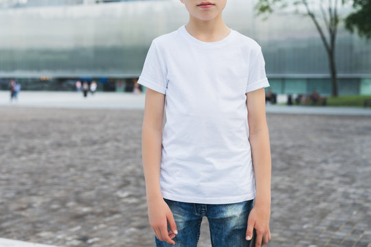 Summer day. Young hipster boy dressed in white t-shirt is stands outdoor. Mock up. Space for logo, text, image.