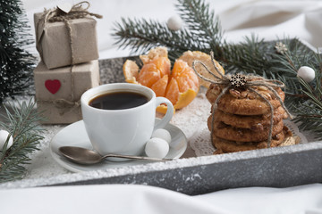 Christmas Breakfast in bed on a tray with snow, gifts, fir-tree and tangerines.
