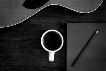 notebook, pencil and coffee cup with acoustic guitar on wooden floor