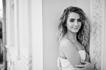 Naklejka premium Stylish curly blonde model girl wear on white posing against old vintage house.