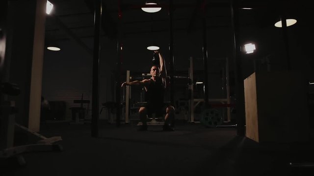 Muscular man doing exercises with weights in the gym. The snatch of the kettlebell.
