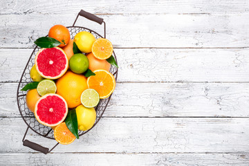 Fresh citrus fruits in basket. Orange, grapefruit, lemon, lime, tangerine. Assorted fresh citrus fruits with leaves. Top view and copy space - obrazy, fototapety, plakaty
