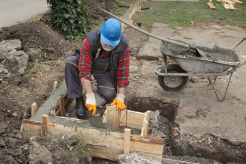 Construction worker making concrete foundation in formwork using trowel