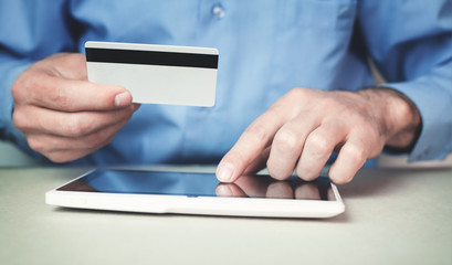 Man holding credit card and using digital tablet.
