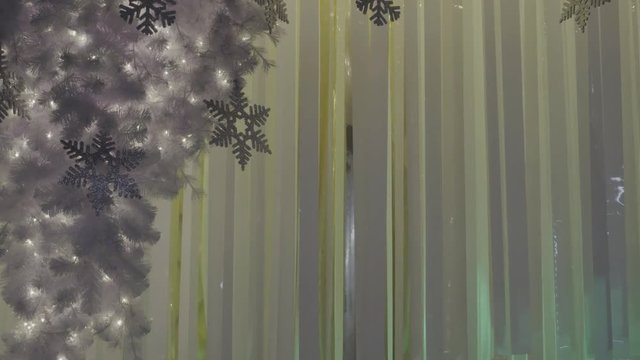Greeting Season concept. Gimbal shot of ornaments on a Big Christmas tree with decorative light and falling snow in 4k (UHD)