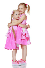 Two little girls hug.