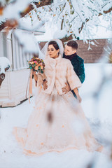 Sensitive portrait of the cheerful beautiful newlywed couple. The groom is heating the hands of his...