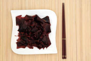Dulse seaweed health food on a porcelain square shaped dish and chopsticks on bamboo background. Super food very high in minerals and has many health benefits.. © marilyn barbone