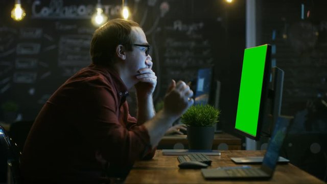 Stressed Office Worker, Exhales and Hits the Table with His Fist in Frustration and Covers His Face in Hands. He's Working on a Personal Computer with Mock-up Green Screen. RED EPIC-W 8K Camera.